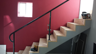 Handrail stairs against red wall.